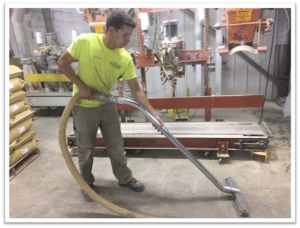 Person using large vacuum to clean dust from floor.