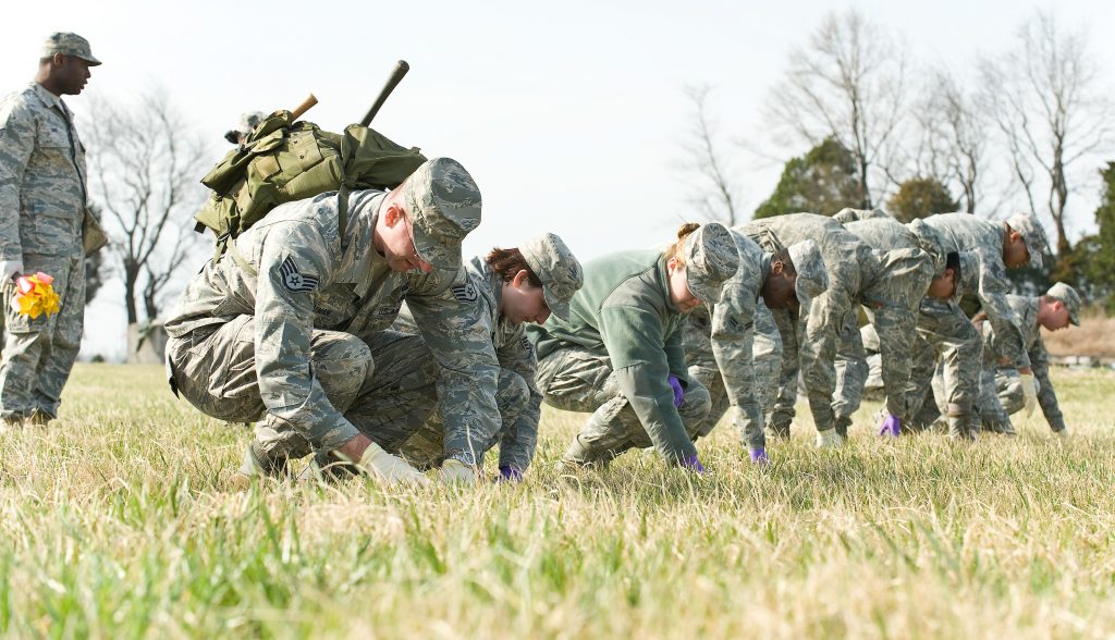 A photo of a group of soldiers conducting a grid search for every piece of evidence